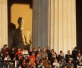 A crowd of people stand in the side steps of the Lincoln Memorial