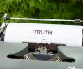 A typewriter holds a piece or paper reading 'truth'