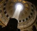 A shaft of light from an opening in a dome lights a cross on a pedestal.