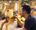 A restorer rest on his elbows while painting a wooden rocking horse.