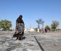 A Sudanese woman walks across the ashes of a burnt out street market.