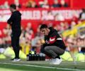 A dejected football coach squats by the byline.