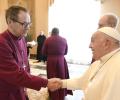 An Anglican bishop wearing purple shakes hands with the Pope.