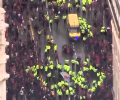 Aerial view of a yellow-jacketed police forming a cordon within a crowd.