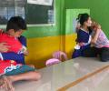 Female prisoners hug their children who have climbed across a table to them.