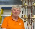 A professor stands next to experimental equipment.