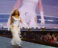 Beyonce marches along a stage catwalk as photographers stare from below.