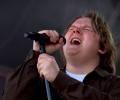 Lewis Capaldi sings with eyes closes, holding a mic and its stand