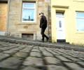 A man walks up a cobble street.