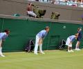 Tennis line judges stand and lean forward with hands on knees