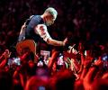 Bruce Springsteen crouches down and holds a hand out to a sea of outstretched hands