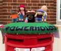 A knitted post box topper shows a group of people and the word powerhouse.