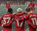 Three Manchester United footballers with their arms around each others backs.