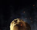 the head of a classical statue looks up amid embers around it.