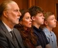 A family sit together watching a trial in a court.