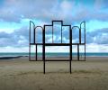 A metak sculpture outlines an altar, stands on a beach.