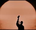 A silhouette of a musician holding up shakers.