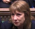 A woman sits and holds back a tear.