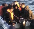 A people sumggler steers an overcrowded small boat.