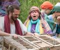 An outdoor theatrical setting shows Jesus with a basket.