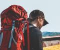 A pilgrim with a red backpack heads off.