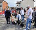 A media pack await a press conference in a street.