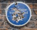 A commemorative blue plaque on a a wall is smashed to pieces