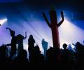 A band and audience are back lit against a stage.