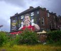 A mural on a side of a pub shows a footballer making a heart sign.