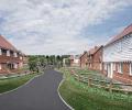 A render of a new housing estate showing a road, wooden fences and clapperboard hosues.