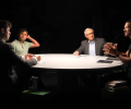 A spotlit round table with podcast guests around it.