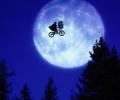 A child and E.T. ride a BMX bike across a moon lit sky.