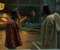 A film character talks to an angel in the street who has wings on the back of his coat.