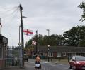 A suburban English street with St George's Cross flags on lamposts. 