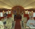 Characters from a Wes Anderson film sit in a stylish plane interior.