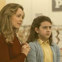 A mother and child, wearing 70s clothing, look to the left.