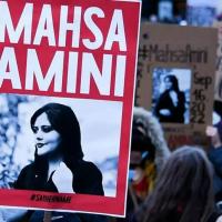 A protester holds a red placard bearing the name and image of Mahsa Amini