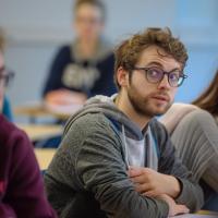 Quizzical-looking students look across a tutorial to others.