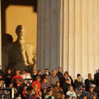 A crowd of people stand in the side steps of the Lincoln Memorial