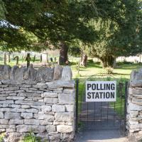 A gate to a churchyard displays a sign saying polling station.