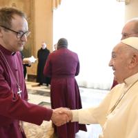 An Anglican bishop wearing purple shakes hands with the Pope.