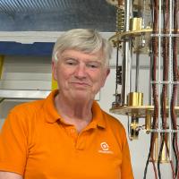 A professor stands next to experimental equipment.