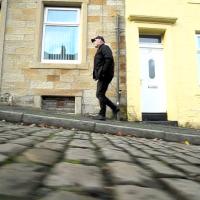 A man walks up a cobble street.