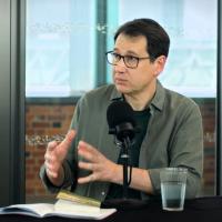 A podcast guest gestures with their hands.