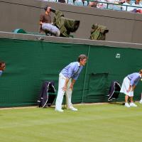 Tennis line judges stand and lean forward with hands on knees