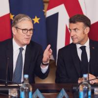 Keir Starmer and Emmanuel Macron in front of flags.