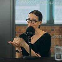 a woman speaks and gestures while recording a podcast