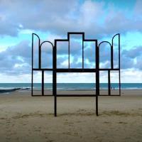 A metak sculpture outlines an altar, stands on a beach.