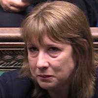 A woman sits and holds back a tear.