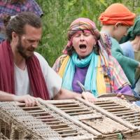 An outdoor theatrical setting shows Jesus with a basket.